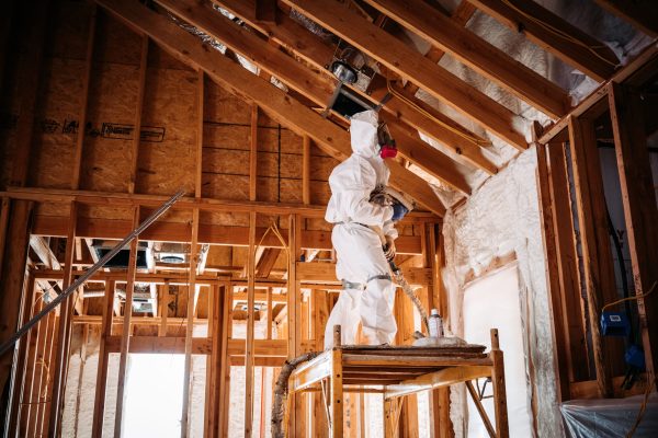 A man in a special white uniform with a mask repairs the wooden roof of a huge building